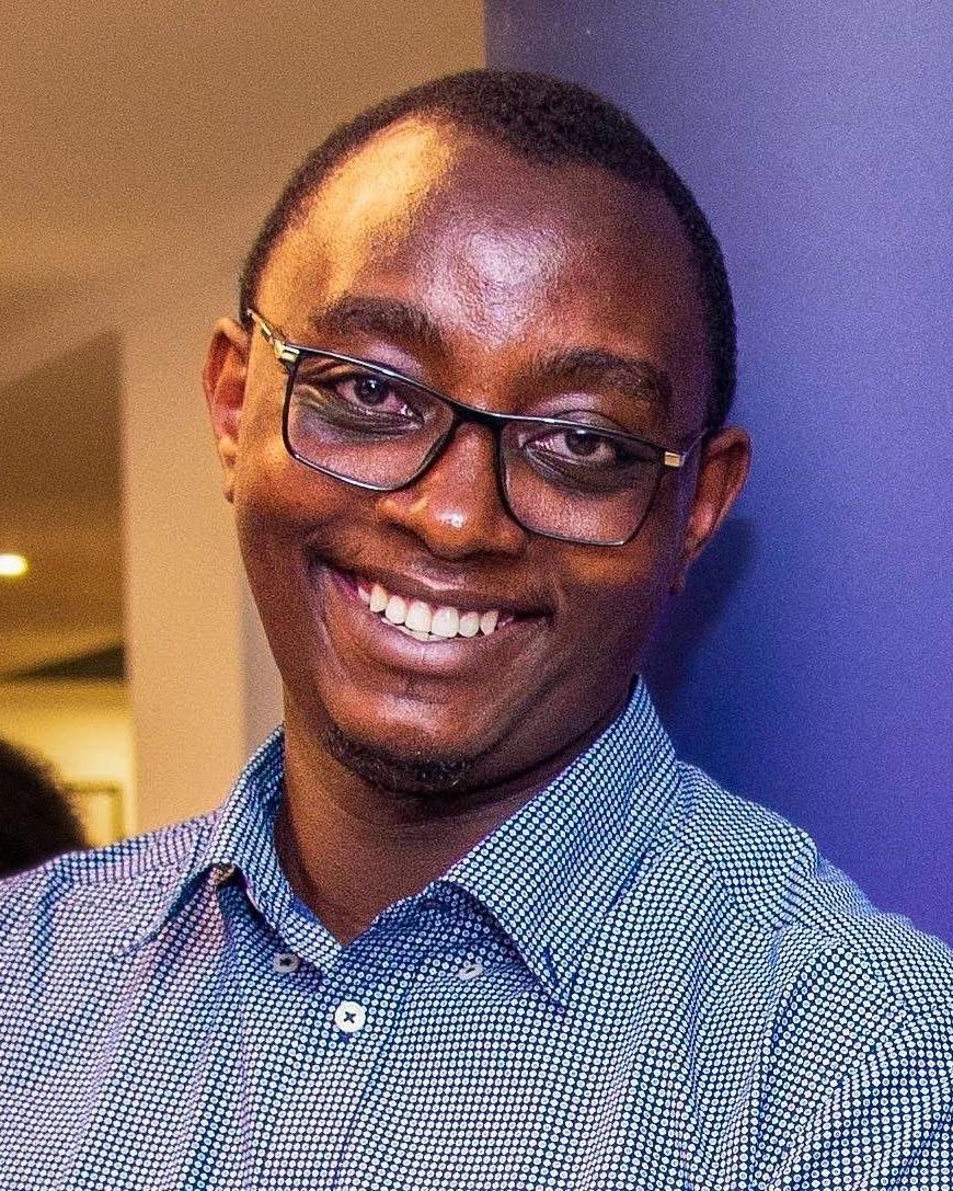 Lawrence Muthoga smiling, in glasses and a blue patterned shirt
